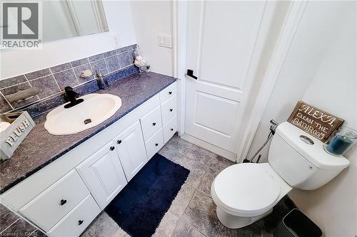 Bathroom featuring a white vanity with heart-shaped pulls, a dark countertop, and a white drop-in sink with a black faucet - 58 East 22Nd Street, Hamilton, ON 