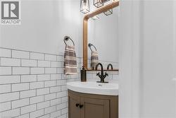 Pedestal sink with dark bronze faucet, set against a subway tile wainscoting - 