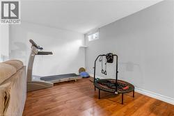 Versatile lower-level room featuring wood-finish flooring, light grey and white painted walls, and a high horizontal window - 