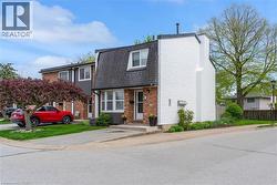 End-unit townhome featuring a gambrel roof and a combination of brick and textured white siding - 