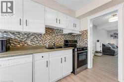 Kitchen featuring white cabinetry, a mosaic tile backsplash, dark countertops, and stainless steel appliances - 