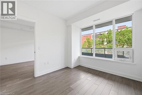 Contemporary room featuring expansive windows, wood-finish flooring, and crisp white walls - 212 King William Street Unit# 418, Hamilton, ON 