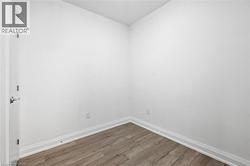 Room featuring neutral white walls, wood-finish flooring, and white baseboards - 