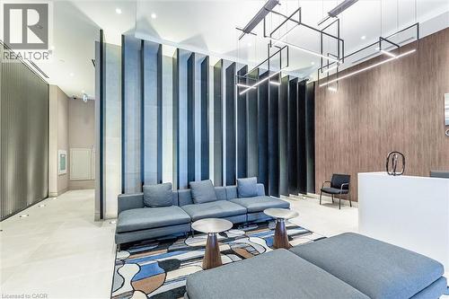 Modern common area featuring a geometric pendant lighting fixture, wood-finish accent wall, vertical slat room divider, and light-toned tile flooring - 212 King William Street Unit# 418, Hamilton, ON 
