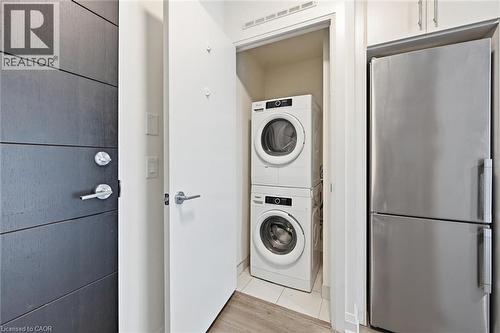 Compact laundry closet featuring a stacked washer and dryer - 212 King William Street Unit# 418, Hamilton, ON 