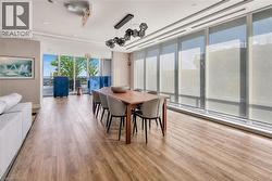 Open-concept room featuring wood-finish flooring, recessed lighting, and a modern geometric pendant light fixture - 