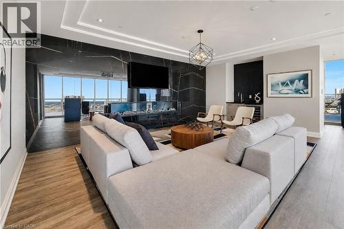 Spacious living area featuring expansive windows, wood-finish flooring, a contemporary fireplace with a dark stone surround, a wet bar, and recessed lighting - 212 King William Street Unit# 418, Hamilton, ON 