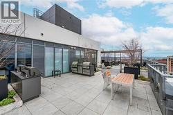 Expansive rooftop patio featuring large format tile flooring, multiple built-in grilling stations, and framed by a modern metal railing - 