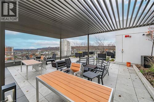 Spacious rooftop patio featuring a slatted pergola, gray paver flooring, and perimeter landscaping - 212 King William Street Unit# 418, Hamilton, ON 