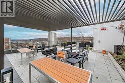 Spacious rooftop patio featuring a slatted pergola, gray paver flooring, and perimeter landscaping - 