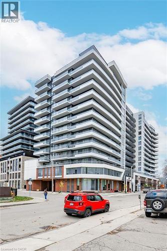 Modern high-rise residential building featuring multiple tiers of private balconies with clear glass railings - 212 King William Street Unit# 418, Hamilton, ON 