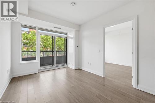 Open-concept room featuring wood-finish flooring, white baseboards, and a glass-paneled sliding door leading to a private balcony - 212 King William Street Unit# 418, Hamilton, ON 