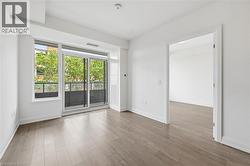 Open-concept room featuring wood-finish flooring, white baseboards, and a glass-paneled sliding door leading to a private balcony - 