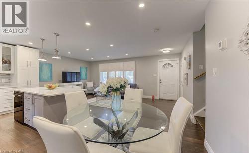 Open-concept living space featuring wood-finish flooring, recessed lighting, and a white kitchen with an island - 619 Forest Hill Drive, Kitchener, ON 