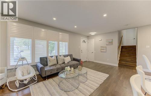 Living area featuring recessed lighting, extensive window treatments, light wood-finish flooring, and a natural wood staircase - 619 Forest Hill Drive, Kitchener, ON 