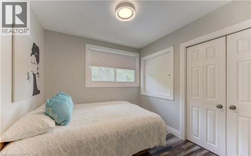 Neutral-toned room featuring wood-finish flooring, a white window frame with roller blinds, and a built-in closet with paneled bifold doors - 619 Forest Hill Drive, Kitchener, ON 