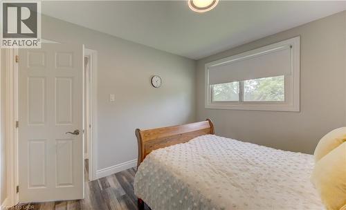 Bedroom featuring wood-finish flooring, a window with roller shade, and a six-panel interior door - 619 Forest Hill Drive, Kitchener, ON 