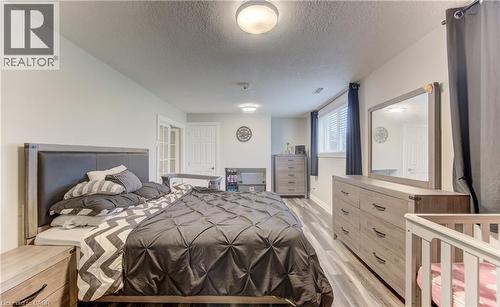 Spacious bedroom featuring wood-finish flooring, light neutral wall paint, a window with horizontal blinds, and a built-in overhead light fixture - 619 Forest Hill Drive, Kitchener, ON 