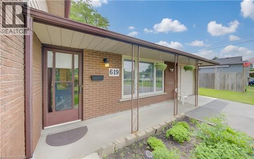 Brick exterior featuring a covered front porch with decorative iron posts and a concrete walkway - 619 Forest Hill Drive, Kitchener, ON 