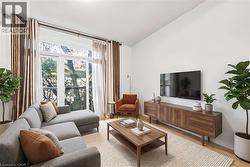 Living room featuring extensive glass doors, light wood-finish flooring, and a neutral color palette - 