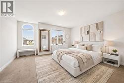 Spacious sleeping area featuring an arched window, white walls, and neutral carpeting - 