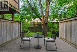 Private outdoor patio featuring paver flooring, tall privacy fencing, and a treed backdrop - 