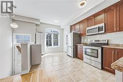 Kitchen featuring stainless steel appliances, wood-finish cabinetry, and a tile backsplash - 