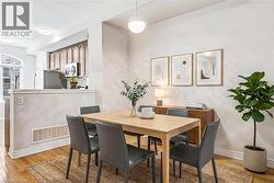 Dining area featuring hardwood flooring, a modern spherical pendant light, and a partial wall separating it from the kitchen - 