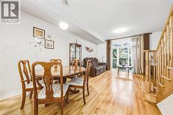 Spacious open-concept living area featuring wood-finish flooring, a bright dining space, and a sliding glass door leading to the exterior - 