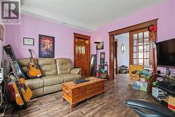 Spacious interior room with wood-finish flooring, light purple wall paint, and white ceiling - 
