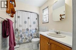 Main Floor bathroom featuring a single vanity with wood-finish cabinetry, a white countertop, and an oval undermount sink - 