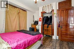 Main Floor Bedroom featuring wood-finish flooring, a built-in closet with wood-finish trim, and a paneled wood-finish door with a transom window - 