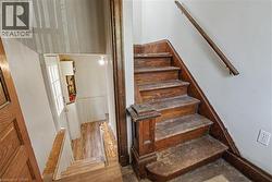 Wood staircase featuring a traditional newel post and handrail, with wood-finish flooring visible below - 