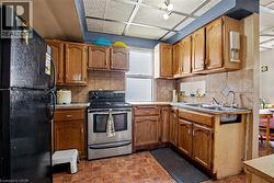 2nd Floor Kitchen featuring wood cabinetry, a double basin sink, a tiled backsplash, and a stainless steel oven range - 