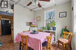 Dining area featuring grid-patterned ceiling tiles, a ceiling fan with integrated lighting, and a double-hung window - 