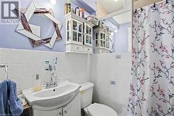 2nd Floor Bathroom featuring a wall-mounted vanity sink with chrome faucet, white subway tile wainscoting, and a decorative wall mirror - 