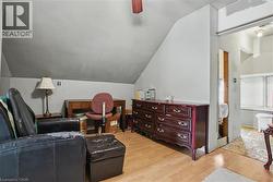 3rd level sitting room featuring sloped ceilings, wood-finish flooring, and a wall opening to a potential walk in closet - 