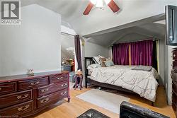 3rd level bedroom  featuring wood-finish flooring, a ceiling fan with integrated lighting, and a wall-mounted television - 