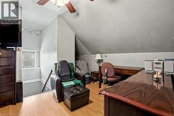 3rd level sitting room featuring sloped ceilings, wood-finish flooring, and a ceiling fan - 