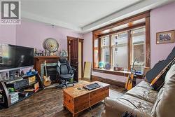 Main Floor Living room featuring a large bay window with wood trim, wood-finish flooring, and a decorative fireplace with a mantel - 
