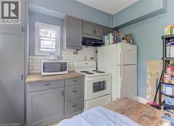 Compact kitchen featuring wood-finish countertops, subway tile backsplash, and painted cabinetry with black hardware - 