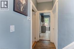 Hallway featuring wood-finish flooring, light blue walls, and white trim - 