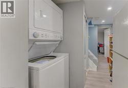 Stacked laundry appliances with a top-load washer, recessed lighting, and light wood-finish flooring - 