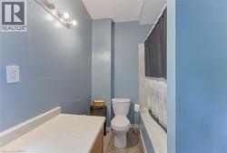 Bathroom featuring a white toilet, light wood-finish flooring, a white countertop with a light wood base, and a tiled shower surround - 