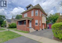 Brick exterior with multiple window styles, covered porch, dormer window, and an attached, paved driveway - 