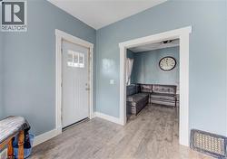 Entryway featuring wood-finish flooring, light blue walls, and white trim - 