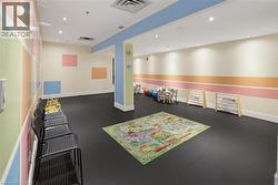 Spacious room featuring dark flooring, recessed ceiling lighting, and walls with colorful striped and block accents - 