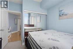 Bedroom featuring light blue walls, carpeted flooring, and a sliding mirrored closet door - 
