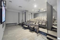 Dedicated theater room featuring tiered seating, a large projection screen, and a ceiling-mounted projector - 