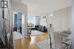 Open-concept living and dining areas featuring wood-finish flooring, white walls, and a large window - 